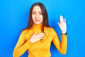 woman yellow shirt blue background swearing in at West Palm Beach injury lawsuit deposition